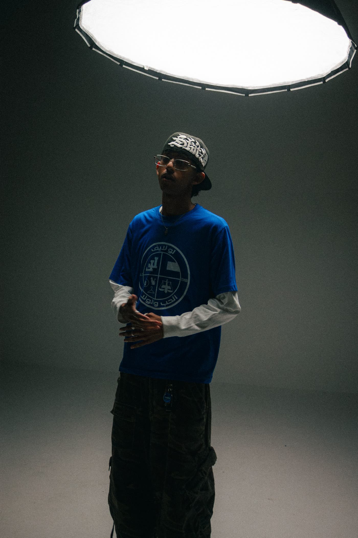 Man in a blue Arabic-print tee under a large softbox