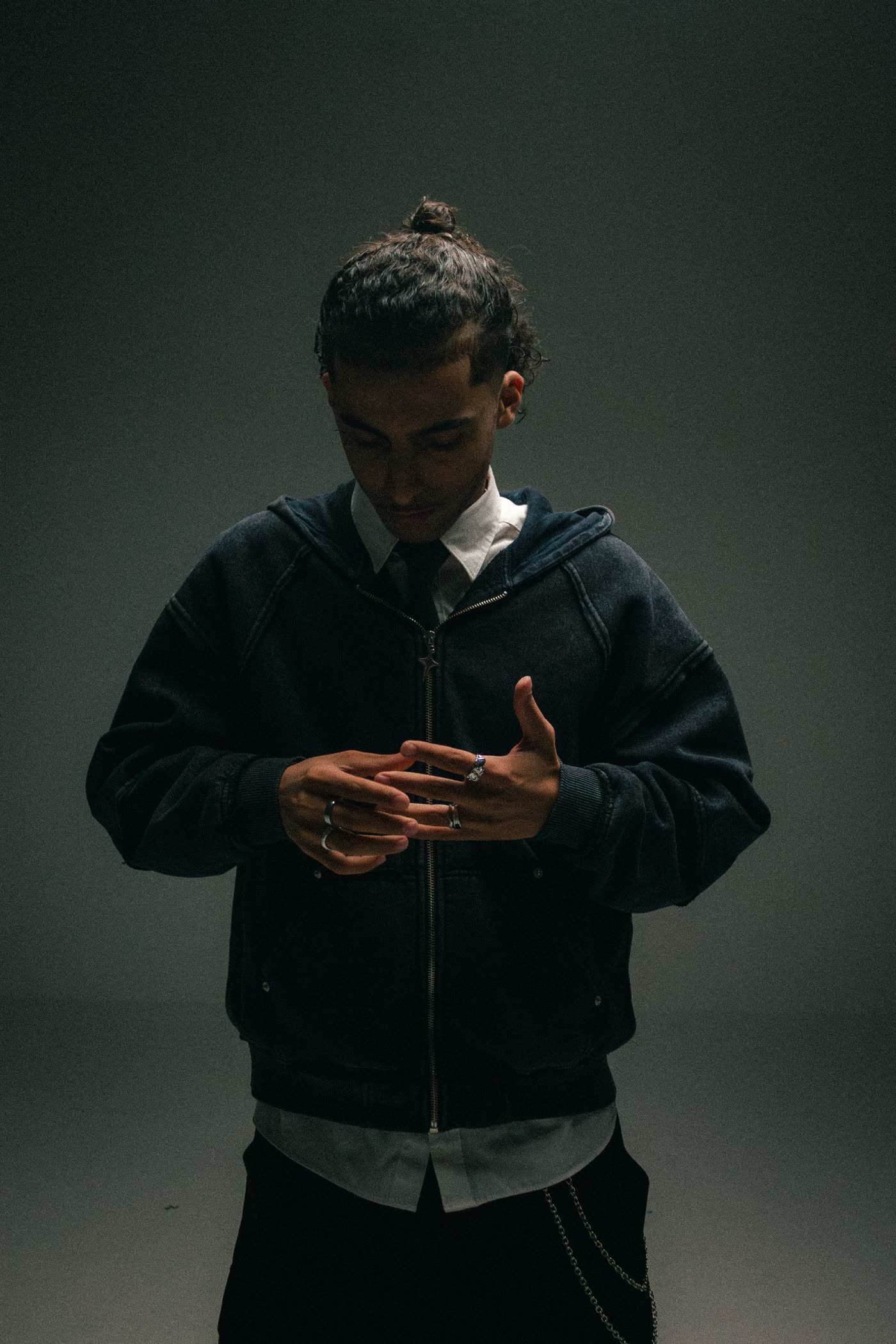 Man in a washed zip hoodie looking down at his rings