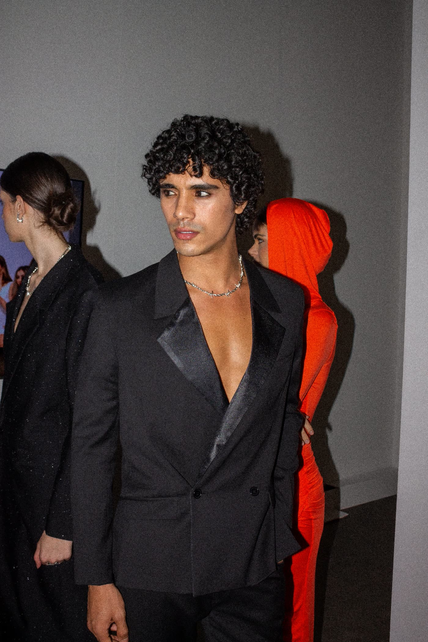Model in an open black tuxedo jacket and barbed-wire chain