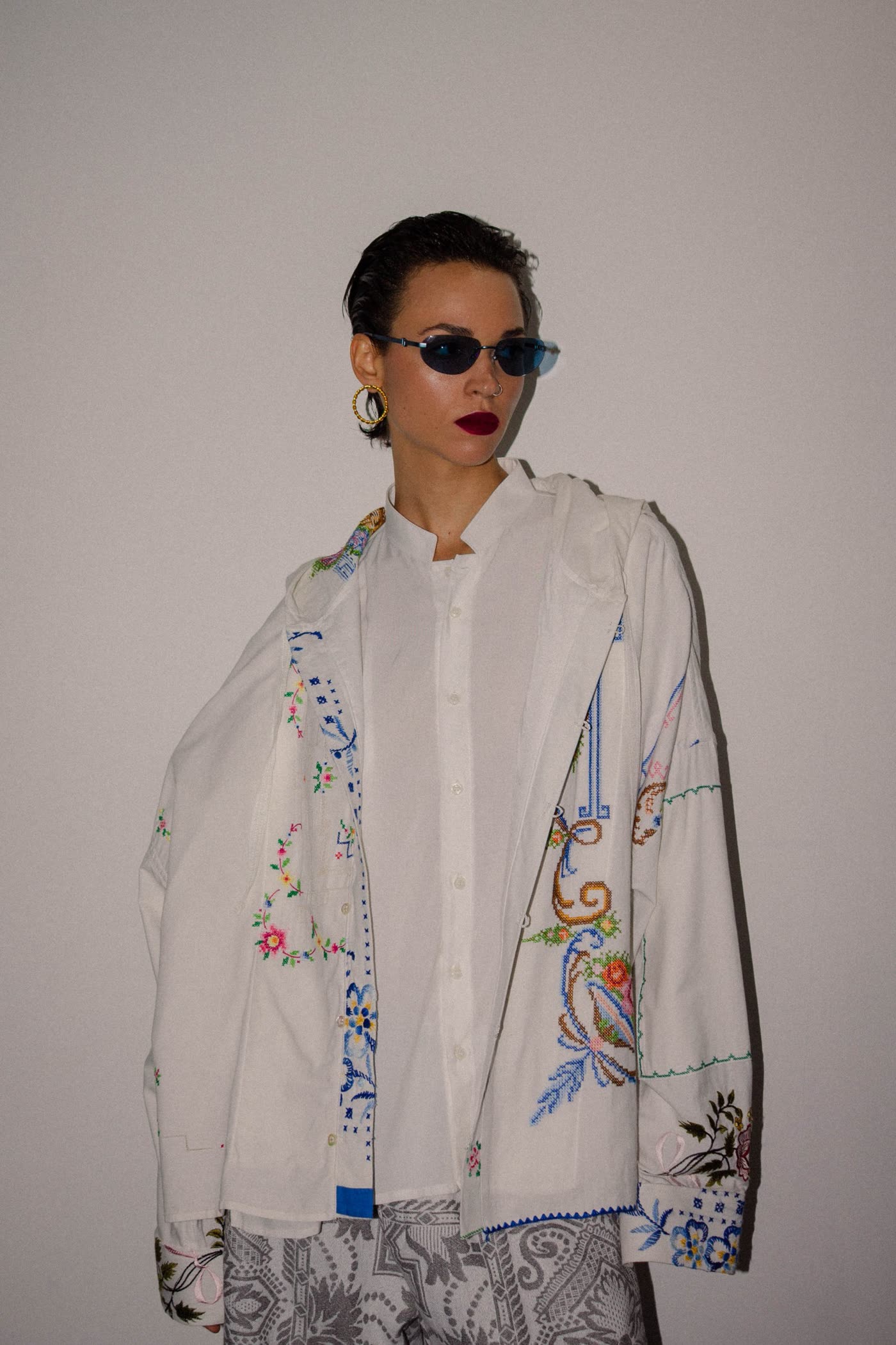 Model in an embroidered patchwork shirt and blue sunglasses