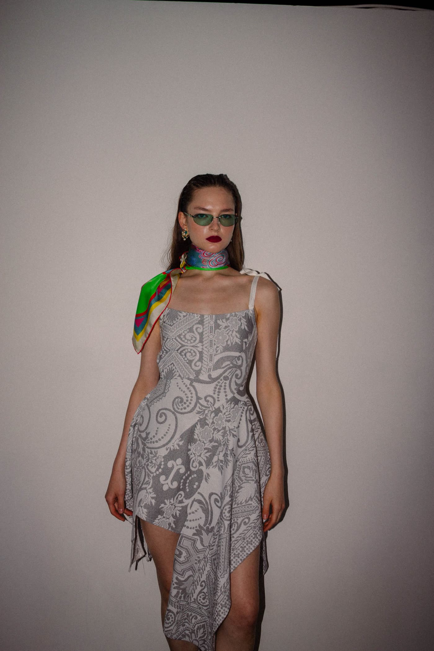 Model in a grey printed dress with a bright silk scarf