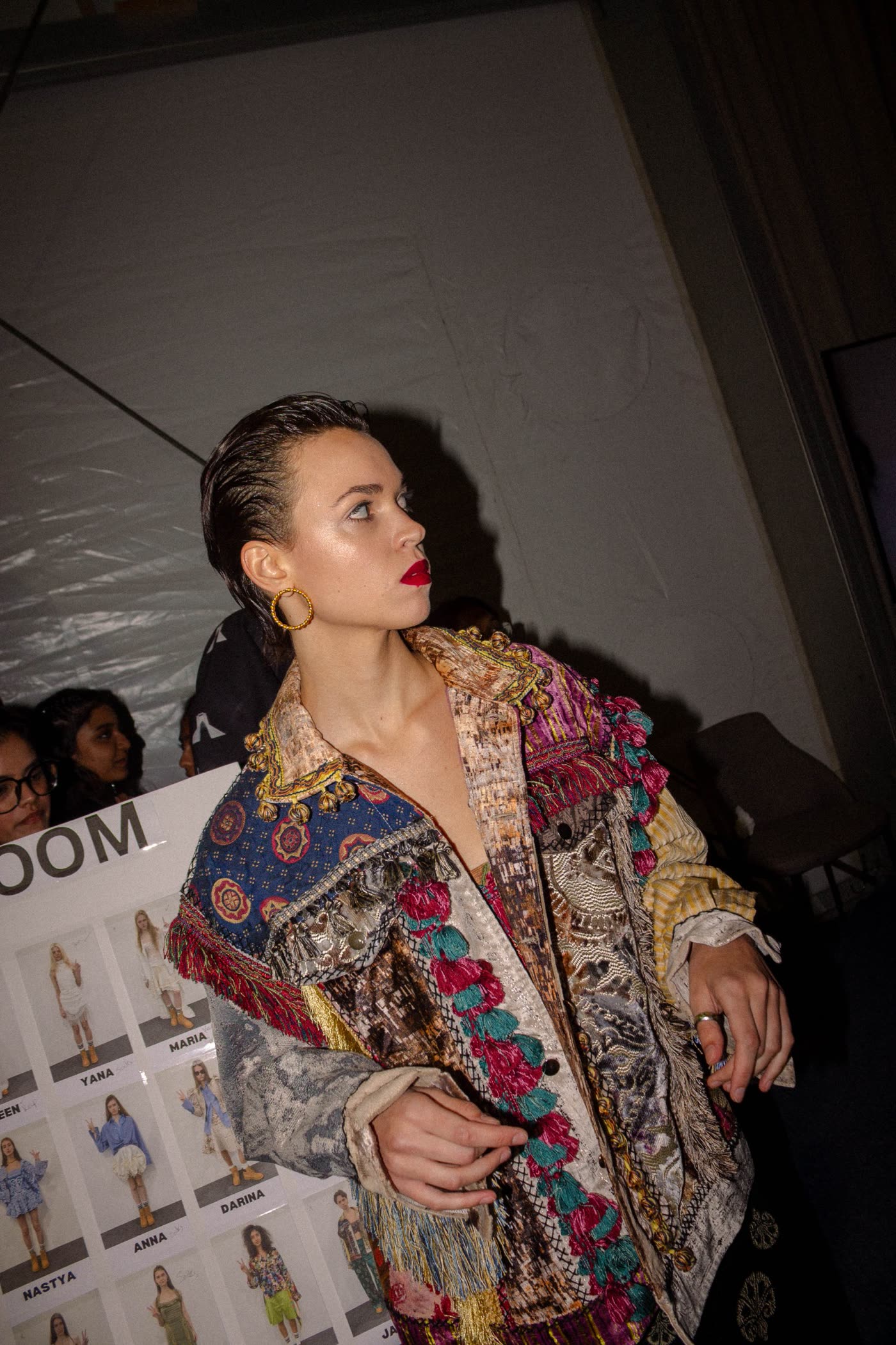 Model in a tasselled patchwork jacket beside the line-up board