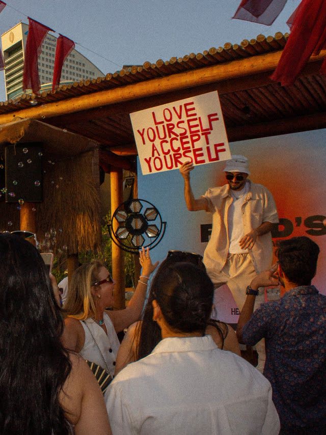 Crowd at an outdoor event with a Love Yourself sign