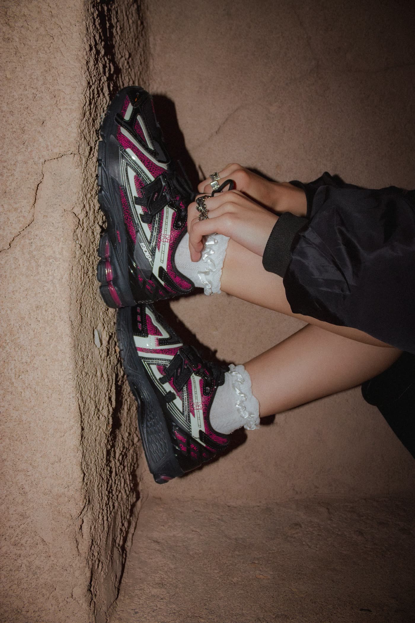 New Balance 1906 sneakers pressed against a clay wall