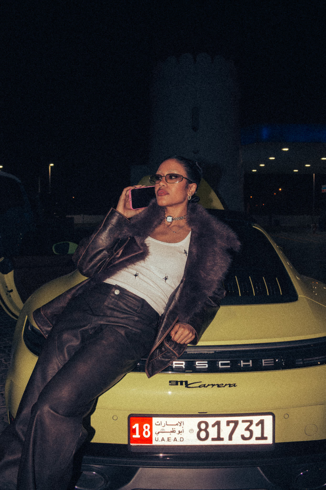 Woman leaning on a Porsche at night