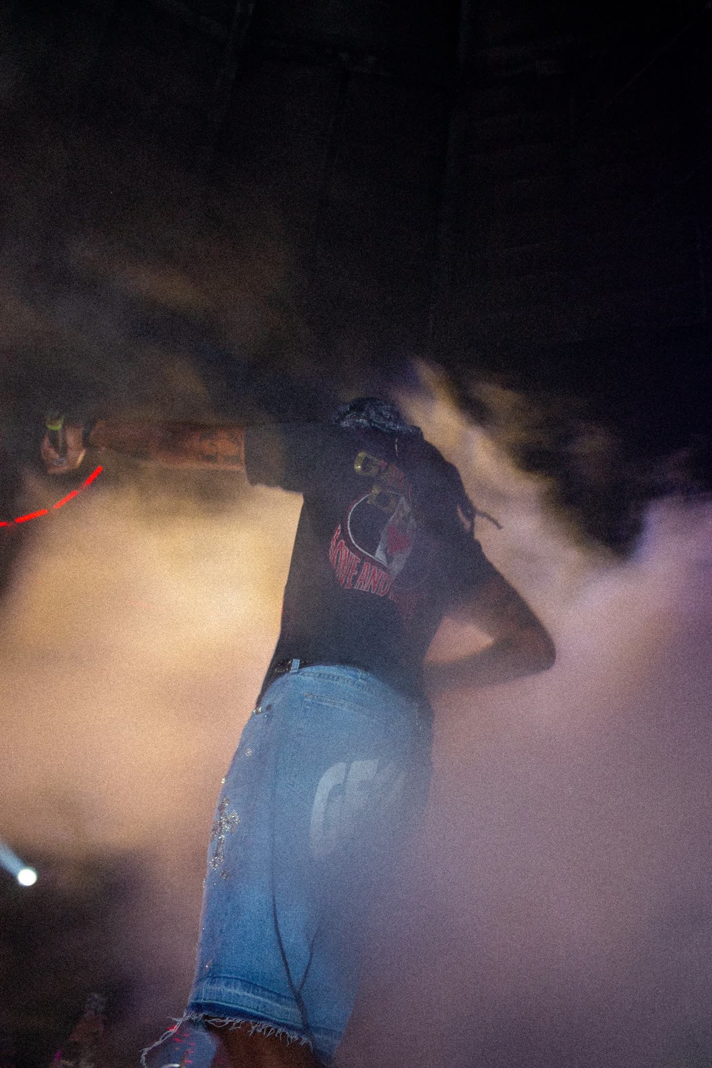 Quavo turned away from the camera in stage smoke and coloured light