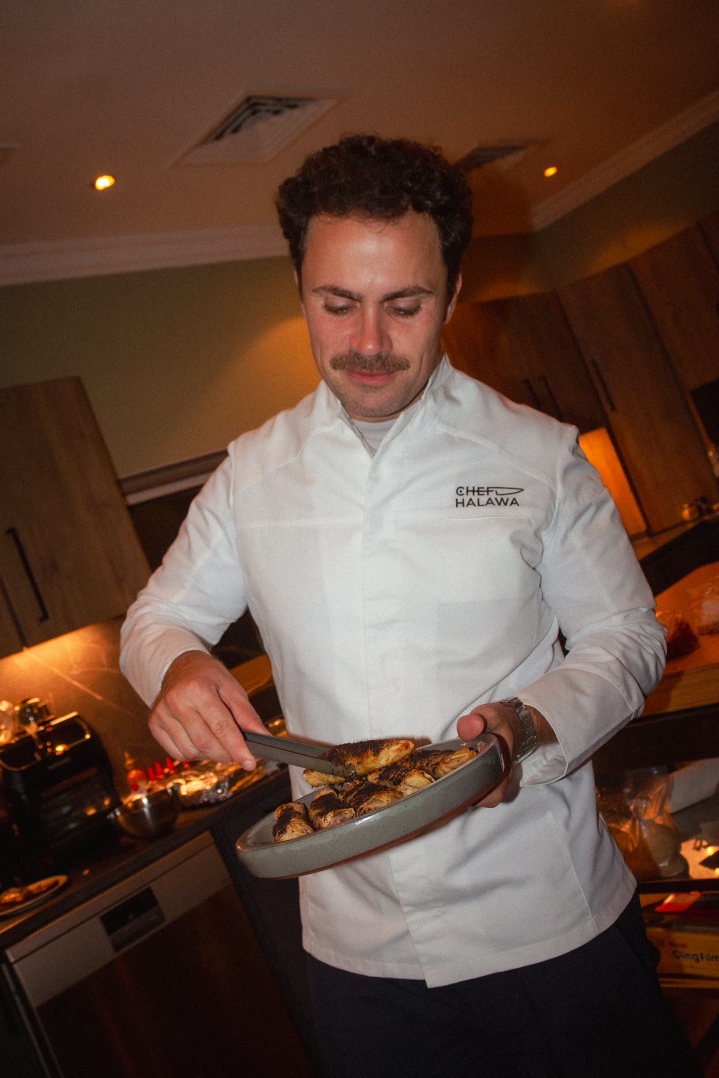 Chef Halawa in his whites serving pastries with tongs in the kitchen