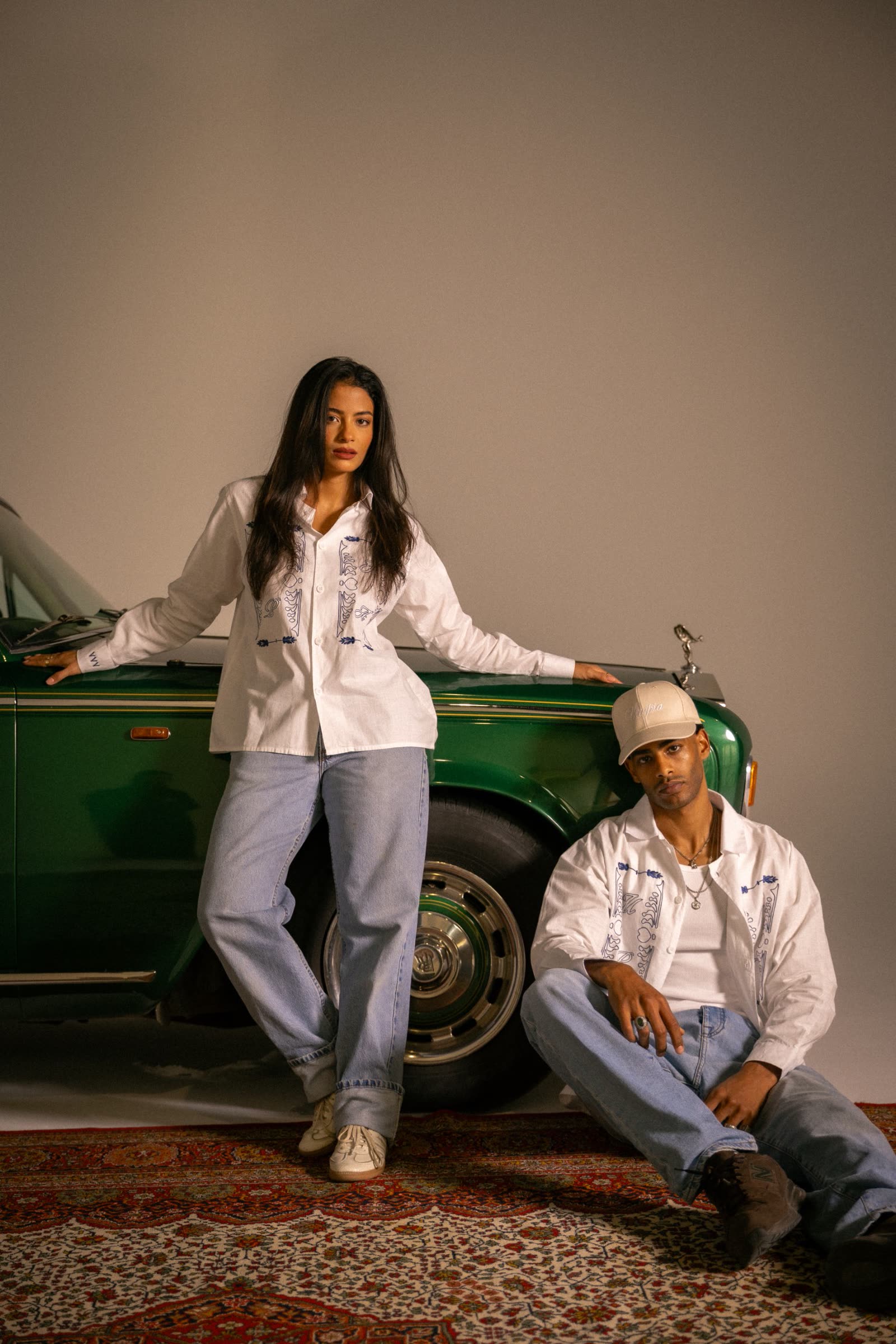 Two models in embroidered Utopia shirts posing by a green Rolls-Royce
